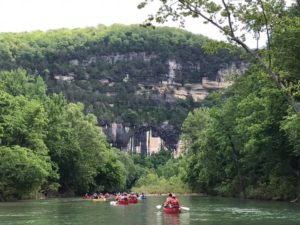 A group of students paddle canoes down a river in Arkansas.